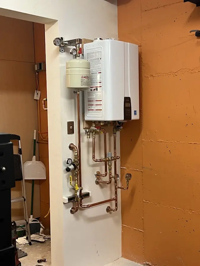 Plumbing technician inspecting water heater connections in Saratoga Springs